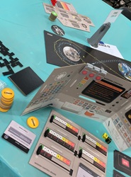 A circular table with several props, a cardboard screen, and a map of a space mission for the Apollo game.
